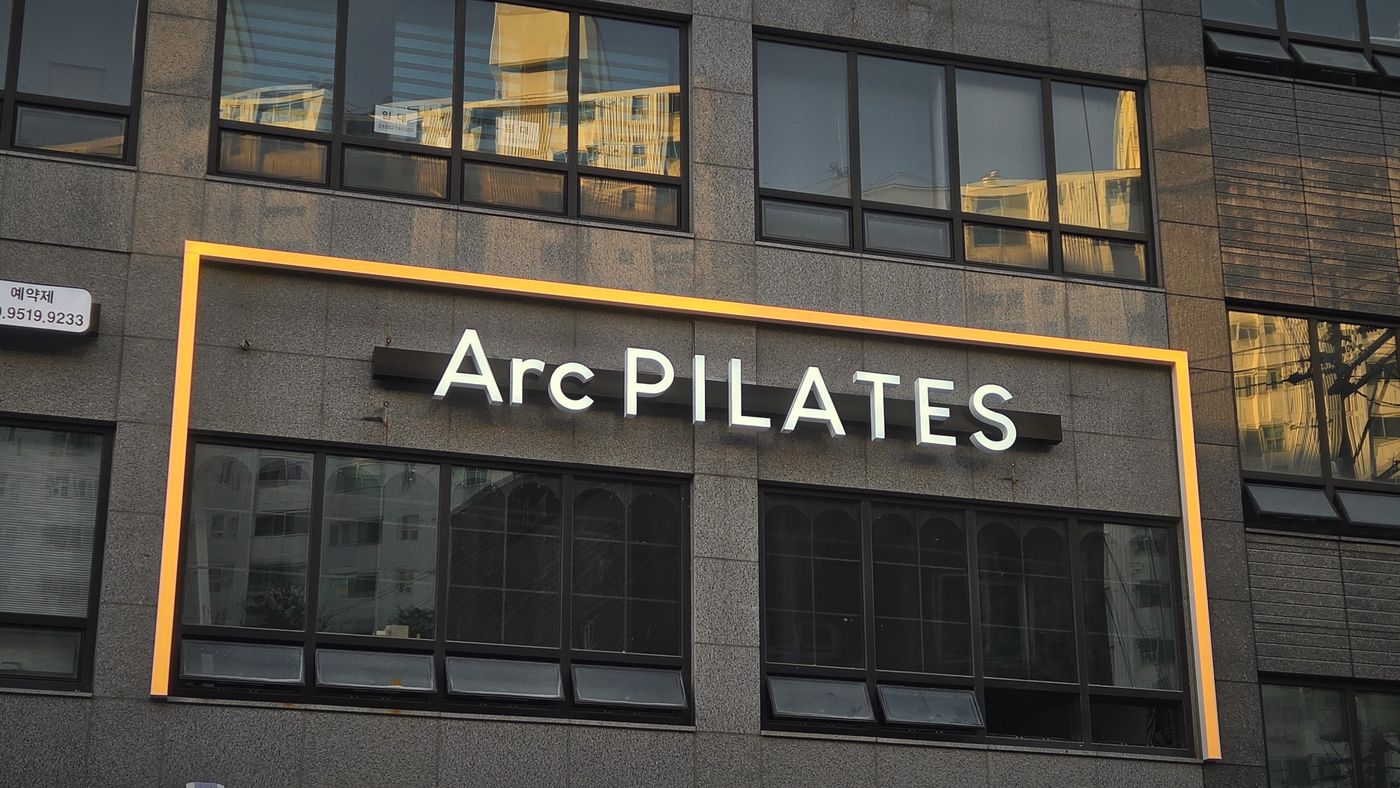 저녁 무렵 불이 켜진 Arc PILATES 외부 간판